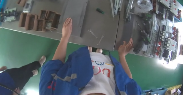 First-person recording of a worker handling components at a real factory workbench